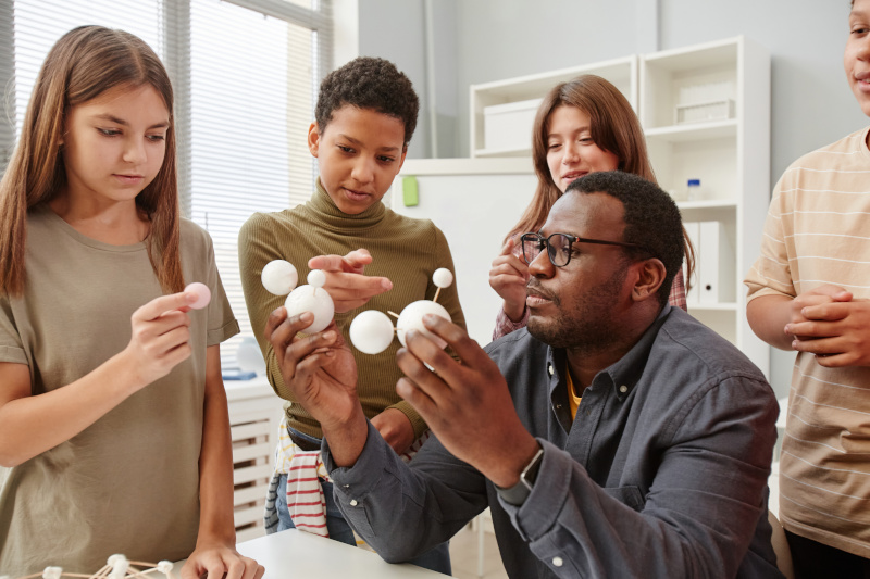 Science teacher showing students molecular structure with foam balls and toothpicks.